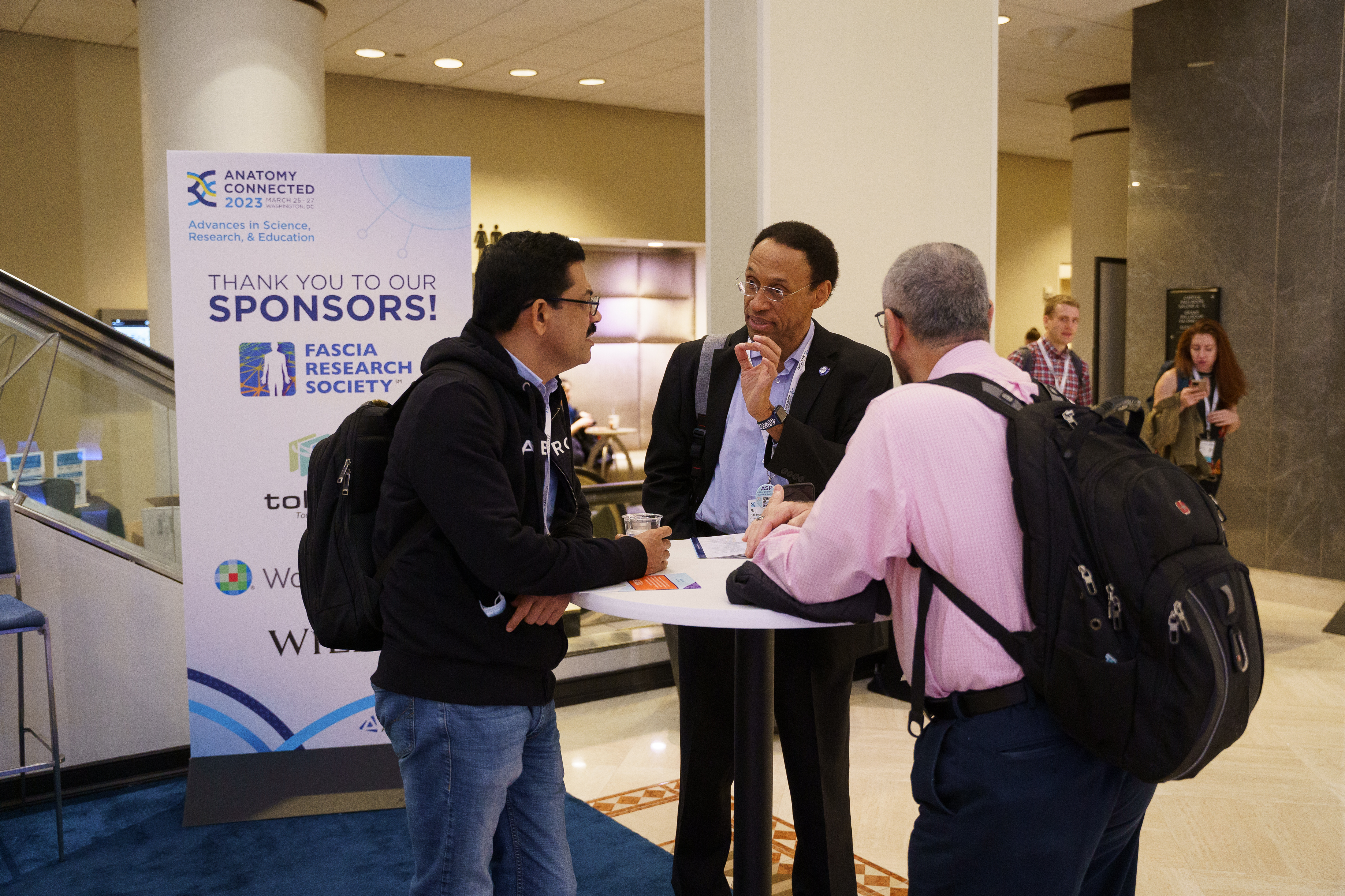 Long time member, Raj Ettarh, speaks to two other members at the annual meeting